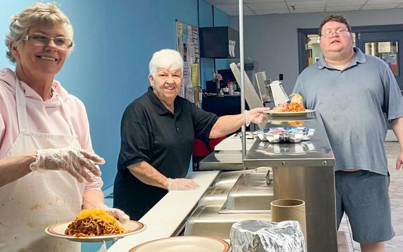 Pictured are Linda Crawford and Dee Jugman serving a meal to Joe Smith.