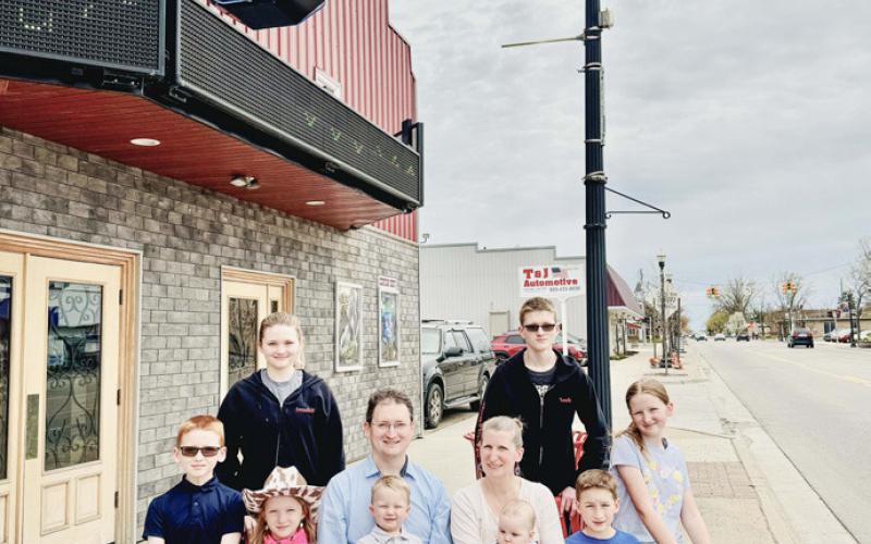 Ian and Tiffany Burgess pose with some potential employees in front of the Beaverton Gem, the theater which they recently purchased.