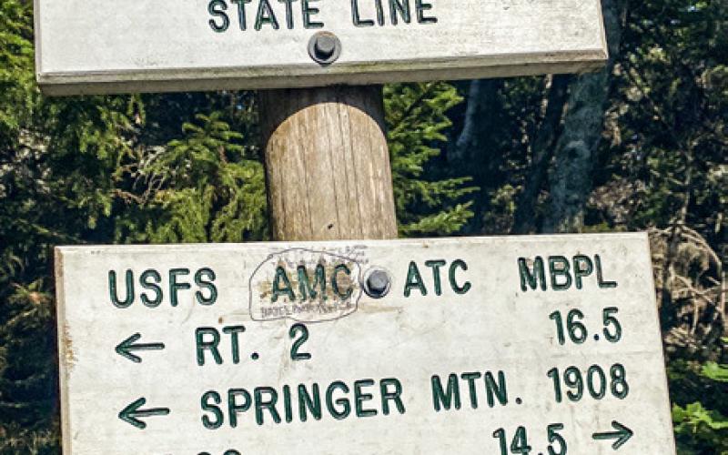 Loren McLaughlin is pictured hiking a tough section of the Appalachian Trail near Newry, Maine. Inset photo is the border sign between New Hampshire and Maine.