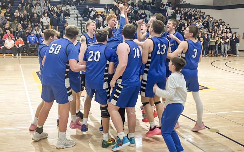 The Gladwin basketball team stormed the court to celebrate with the trophy after winning the Division 2 District Tournament at Shepherd Friday night.