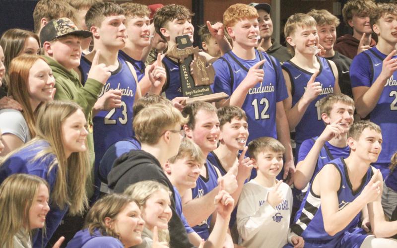 Gladwin’s players and some of their biggest fans gather for a group photo on the court at Shepherd Friday night after the Flying G’s won their first district championship since 2009.