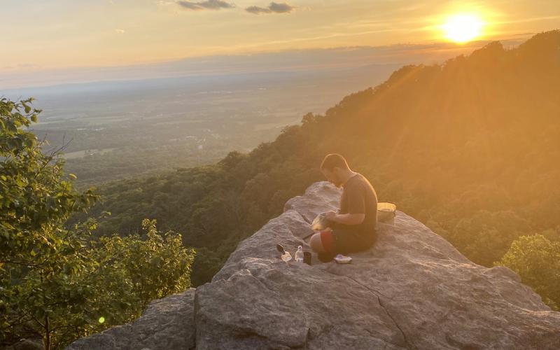 Pictured at far left is a view of the Blue Ridge parkway. At left is McLaughlin standing next to the halfway point designation. Pictured above is John Del Percio having his supper after a long day of hiking in Maryland. He is sitting overlooking the valley below at Annapolis Rock. Inset photo is the front of the Appalachian Trail Conservancy in Harpers Ferry, Virginia.