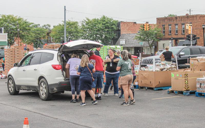 Volunteers help load vehicles with food at CMDHD food distribution event.