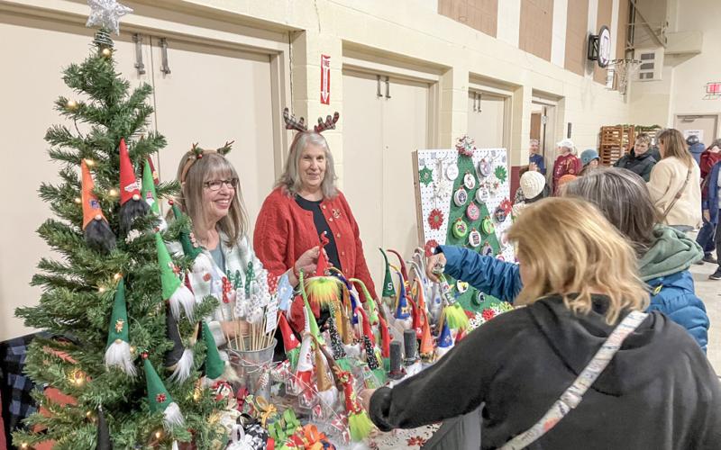 Shoppers check out the Christmas decorations at one of the many colorful booths at the Sacred Heart Bazaar last weekend.