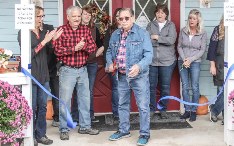 Baker-Kehoe Realty LLC and The Coffee Table Salon staff watch Don Kehoe cut the ribbon at the grand opening of the new Baker-Kehoe Realty LLC location at 1557 W. M-61.