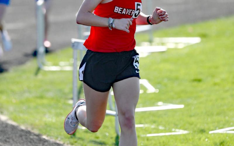 Pictured at right, Taj Spencer, sporting his trusty headband as he competes in the 1600-meter race. At left, Tessa Wohlschlegel trucks along in her evening of running both the 1600-meter and the 3200-meter.