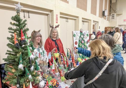 Shoppers check out the Christmas decorations at one of the many colorful booths at the Sacred Heart Bazaar last weekend.