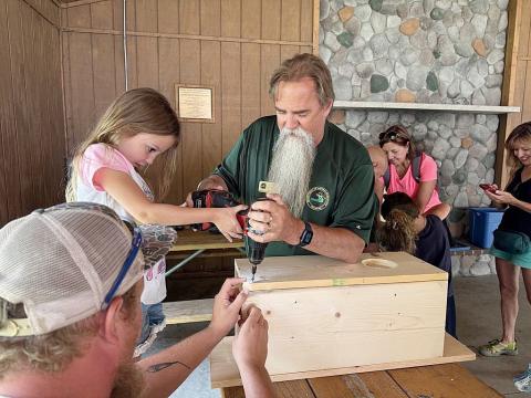 DNR staff help children build wood duck boxes to take home and install in trees near wetlands. These boxes have helped restore wood duck populations throughout Michigan.