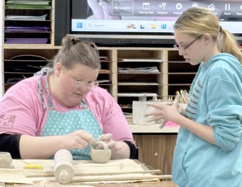 Amber Billman assists a student working on their clay bowl.