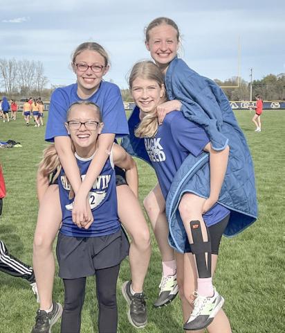 Lily Leinenger and Aria Rule get lifts from Ava Kiger and Avery Graybill after competing in the 400 relay at a junior high track meet last week.