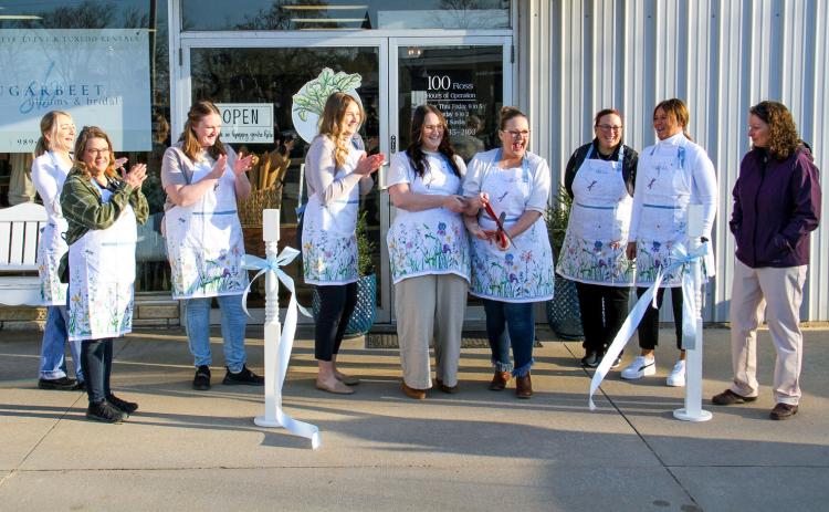 Pictured above, Sugarbeet Blooms and Bridal held a grand opening ceremony for their store at 100 Ross St. in Beaverton on Monday, March 20. Store owner Kim Shea (with the scissors) stands with store manager Clarity Gerow (left of Kim) and co-owner Kennedy Cripps (left of Clarity) as they officially open the store to the public. Pictured below, a large crowd made their way inside afterward to mingle and shop.