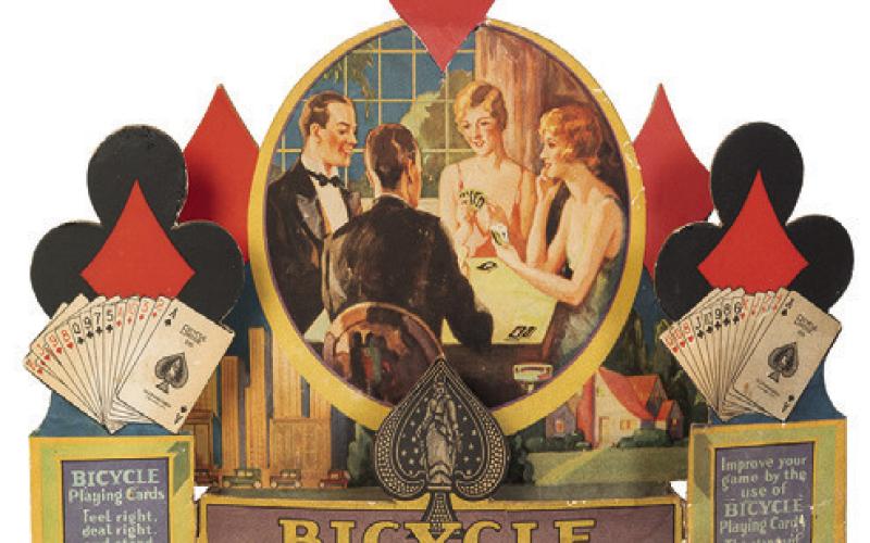 When advertisements include pictures of people, their clothing and hairstyles can help date the item. This store display for Bicycle Playing Cards is from about 1930. KOVELS.COM