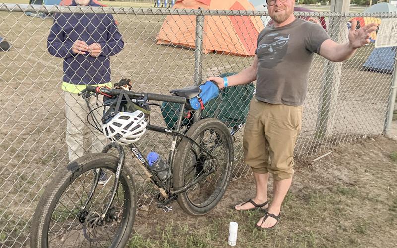 DALMAC ride cyclist Keith Buchley (right) of Lansing relaxes before spending Thursday night in the parking lot at Gladwin High School on his way to Mackinaw City.