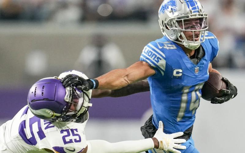 Detroit Lions wide receiver Amon-Ra St. Brown (14) breaks a tackle by Minnesota safety Theo Jackson (25) during the second half of an NFL football game, Sunday, Dec. 24, 2023, in Minneapolis. The Lions won 30-24. AP PHOTO/ABBIE PARR
