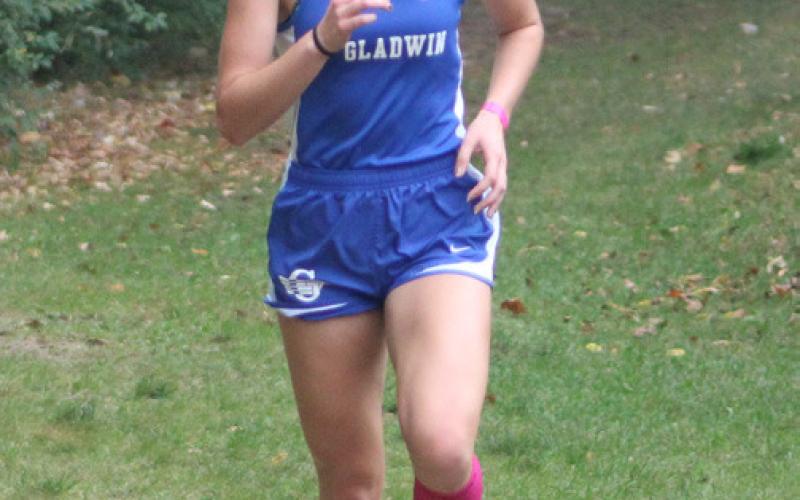 At left, Abby Robinson ran fourth to lead the Gladwin girls’ cross country team to a second-place finish and Tessa Wohlschlegel, at right, from Beaverton races to the finish line last Wednesday at the Jack Pine Conference jamboree at the Gladwin County Recreation Area.