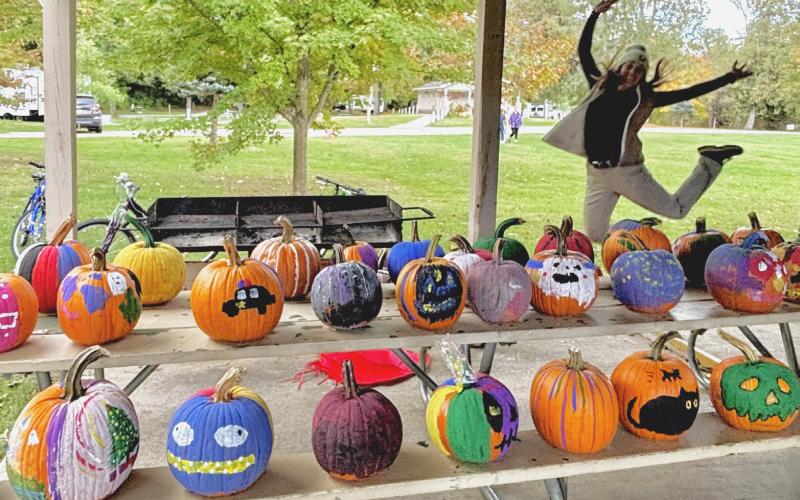An excited Park Manager Sabrina Battjes shows off the colorful collection of pumpkin masterpieces created by local families, now displayed along Cedar Avenue for all to enjoy.