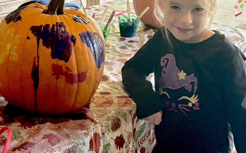 A young artist proudly shows off their creativity during the city’s community pumpkin painting event.