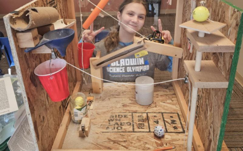 Ember Piper posing with her Rube Goldberg machine she made for Mission Possible.