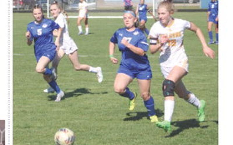 Gladwin’s Reegan Searfoss races an Ogemaw Heights attacker for a loose ball during last week’s district game.
