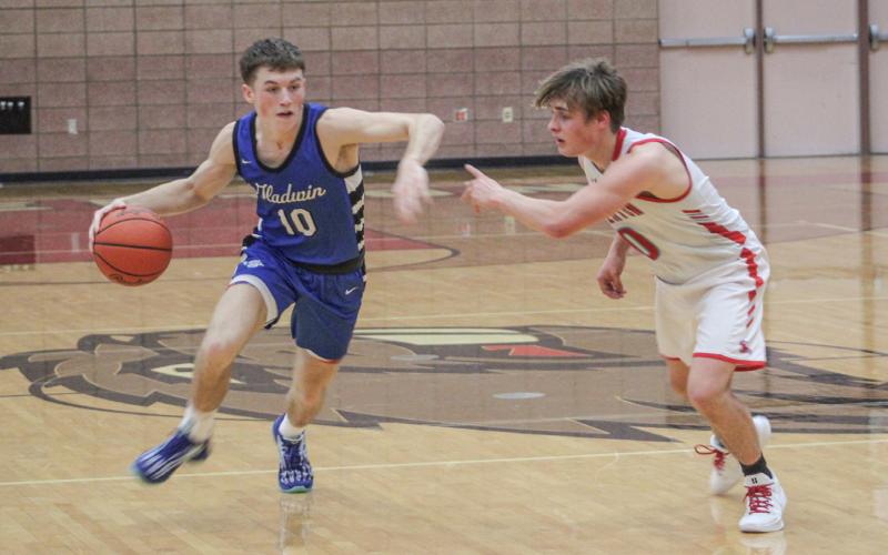 Gladwin’s Seth Mead fends off the defensive pressure applied by Beaverton’s Caiden Loar last Monday night as the Flying G’s won the Battle For Butch.