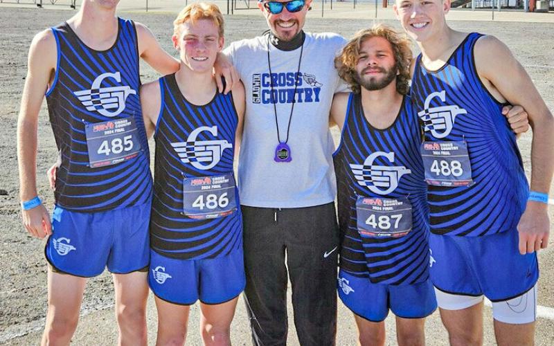 One of the most decorated senior classes in Gladwin cross country history poses with Coach Jordan Strohkirch after finishing eighth at the state meet.