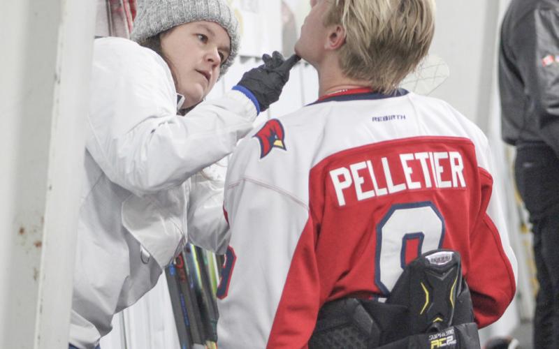 Trainer Lauren Wetmore helps Saginaw Valley State’s Max Pelletier deal with a minor facial laceration during Sunday’s game at Gladwin Community Arena.