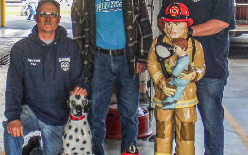 Pictured is Bill Webb (at left) and Scott Grice (at right) Julius Sinischo (at center) with the statues he restored for the Gladwin Rural Urban Fire Department.