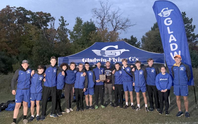 Gladwin’s boys’ cross country team spends some quality time with the Jack Pine Conference trophy after winning a third straight championship Thursday at Harrison.