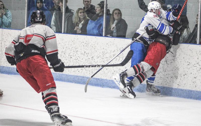 Gladwin’s Hunter Simpson checks in behind the net with a big hit on a Jackson United rival during Saturday’s home opener.