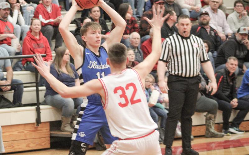 Gladwin’s Brayden Randle holds the ball high and looks for an open teammate while Beaverton’s Jace Mishler applies defensive pressure.