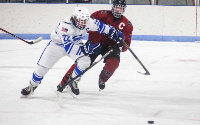 Gladwin’s Treyton Siegert wards off a defender and charges toward the puck during Friday night’s victory over Jackson United.