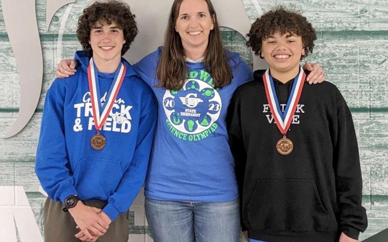 Myles Robinson, coach Sara Christensen, and Michael Ross after the medal ceremony. The boys have their eighth place medals for meteorology.
