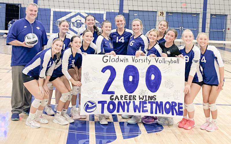 The Gladwin volleyball team celebrates with Coach Tony Wetmore after delivering his 200th career victory last Wednesday by sweeping visiting Standish.