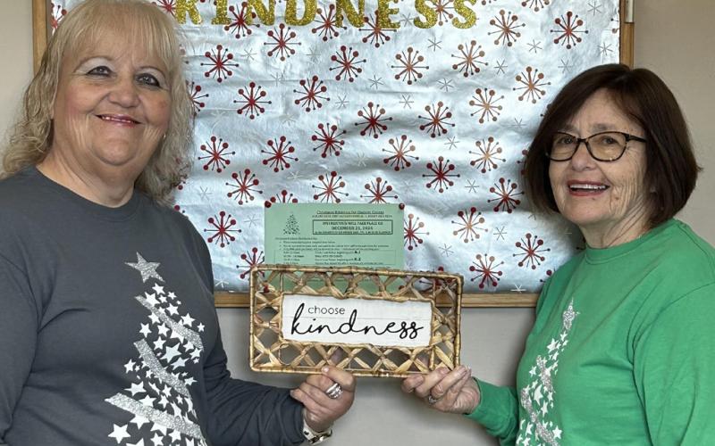 The main two Christmas Kindness office employees, Brenda Povey (left) and Carolyn McNamara (right), hold up a sign that says “Choose Kindness.”