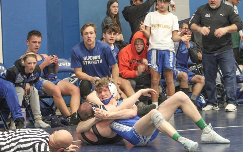 Gladwin’s Drake Ross gets ready to pin his Lakeville opponent as the referee and his teammates look on during Saturday’s dual-meet tourney.