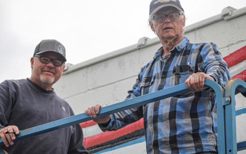 Local artists Eric (left) and Lynn Morgan are busily creating a mural honoring the military on the wall of Americal Legion Post 171.