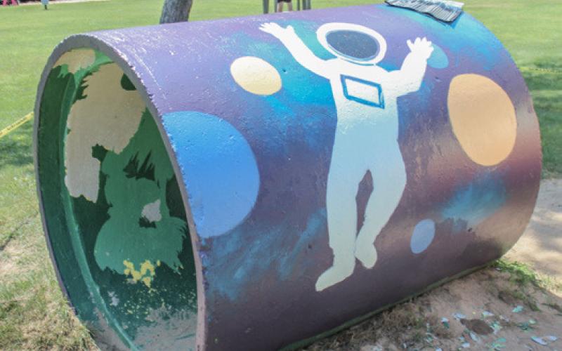High school student paints City Park playground equipment