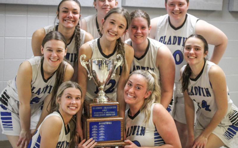 Gladwin’s girls’ basketball team poses with the spoils of victory after topping Beaverton for the Cedar Cup.