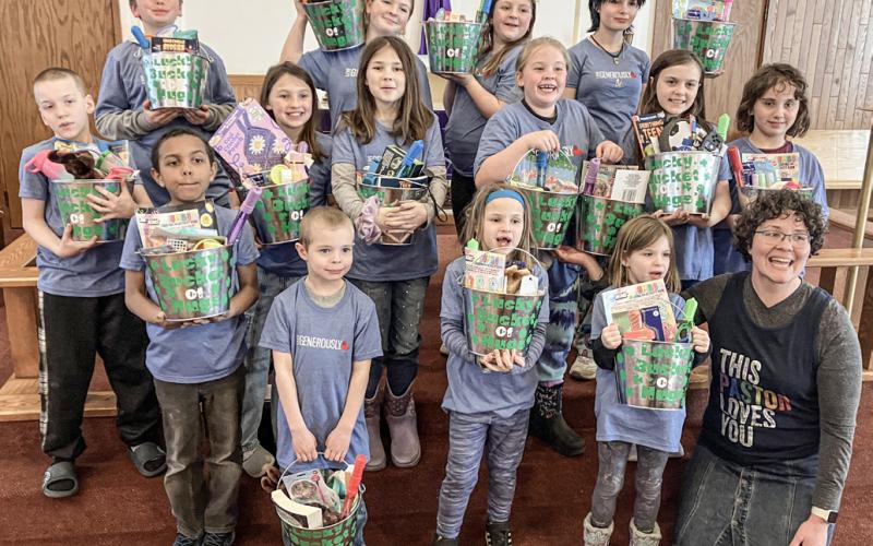 The members of the Kids’ Club show off the buckets of goodies they assembled for foster children with Christ the King Pastor Emily Olsen-Brandt.