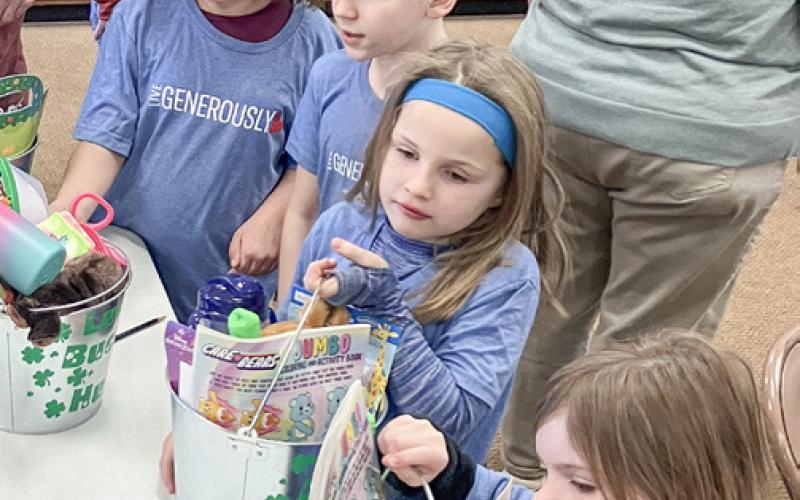 Christ the King Kids’ Club members assemble St. Patrick’s Day-themed gift buckets that will be presented to foster children in the community.