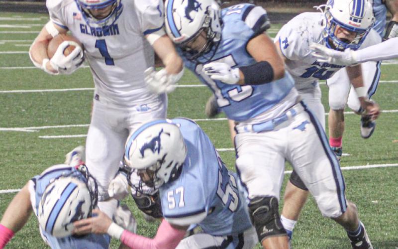 Gladwin’s Trace Corlew steps through a pair of fallen Meridian defenders and wards off another during Friday night’s victory.