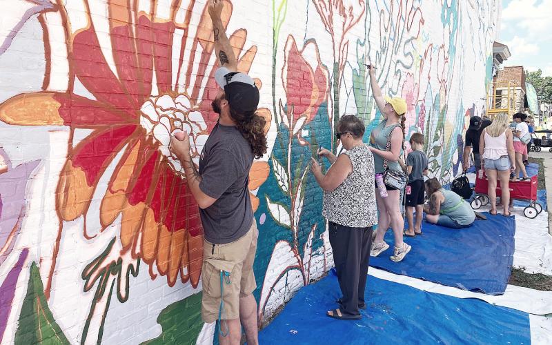 Street Fest attendees helping to finish the mural on the Edward Jones Financial Advisory building on Cedar Ave. GLADWIN