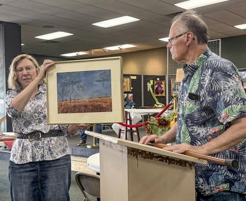 Jan Berg-Rezmer holds Connie Maedel Diehl’s painting while 2025 Art Judge Lynn Morgan comments as to why he chose the pastel titled, Forgotten Pasture, for a third place award in the General Art category.