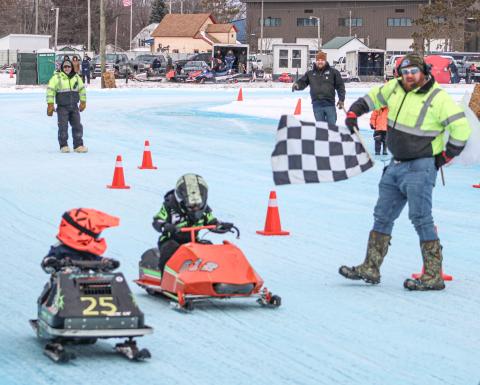 Two drivers in the Kitty Cat Division take the checkered flag at the year’s first Vintage Snowmobile Race at the Gladwin County Fairgrounds.