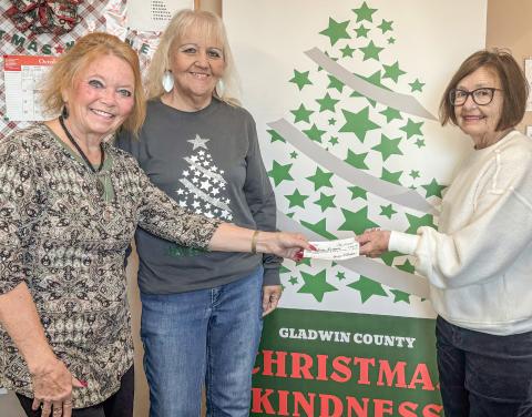 Jan Hudson (at left) presents a check to Christmas Kindness office girls, Brenda Povey (center) and Carolyn McNamara (at right).