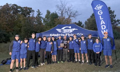 Gladwin’s boys’ cross country team spends some quality time with the Jack Pine Conference trophy after winning a third straight championship Thursday at Harrison.