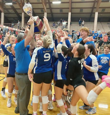 Gladwin coach Tony Wetmore holds the Cedar Cup aloft as his team celebrates after beating Beaverton in five sets last week to retain possession of the trophy.