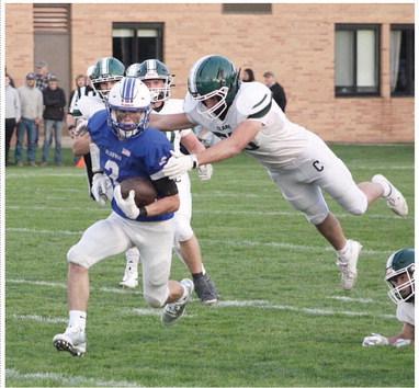 Gladwin’s MJ McDonald runs away from a leaping Clare defender during Friday night’s 14-13 victory that left the Flying G’s alone atop the Jack Pine conference standings with a 3-0 record.