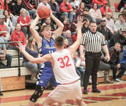 Gladwin’s Brayden Randle holds the ball high and looks for an open teammate while Beaverton’s Jace Mishler applies defensive pressure.