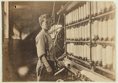 John Dempsey, said to be 12-years-old, working in the mule-spinning room at Jackson Mill, Fiskeville, R.I. in 1909. PHOTO BY LEWIS WICKES HINE FOR THE NATIONAL CHILD LABOR COMMITTEE